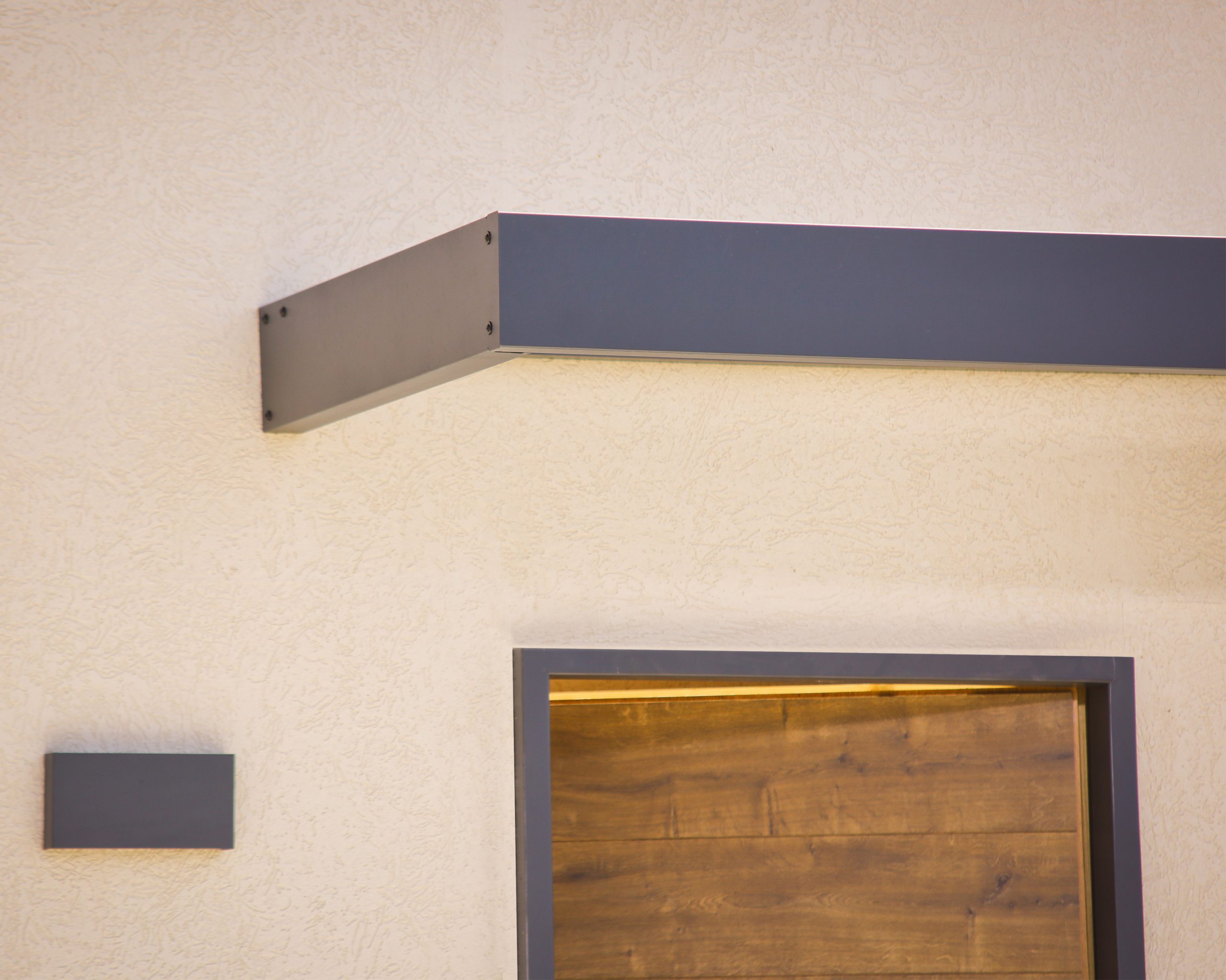 Sophia 2150 door canopy featuring a sleek dark grey aluminum frame above a wooden door, enhancing home entrance with modern style and functionality.