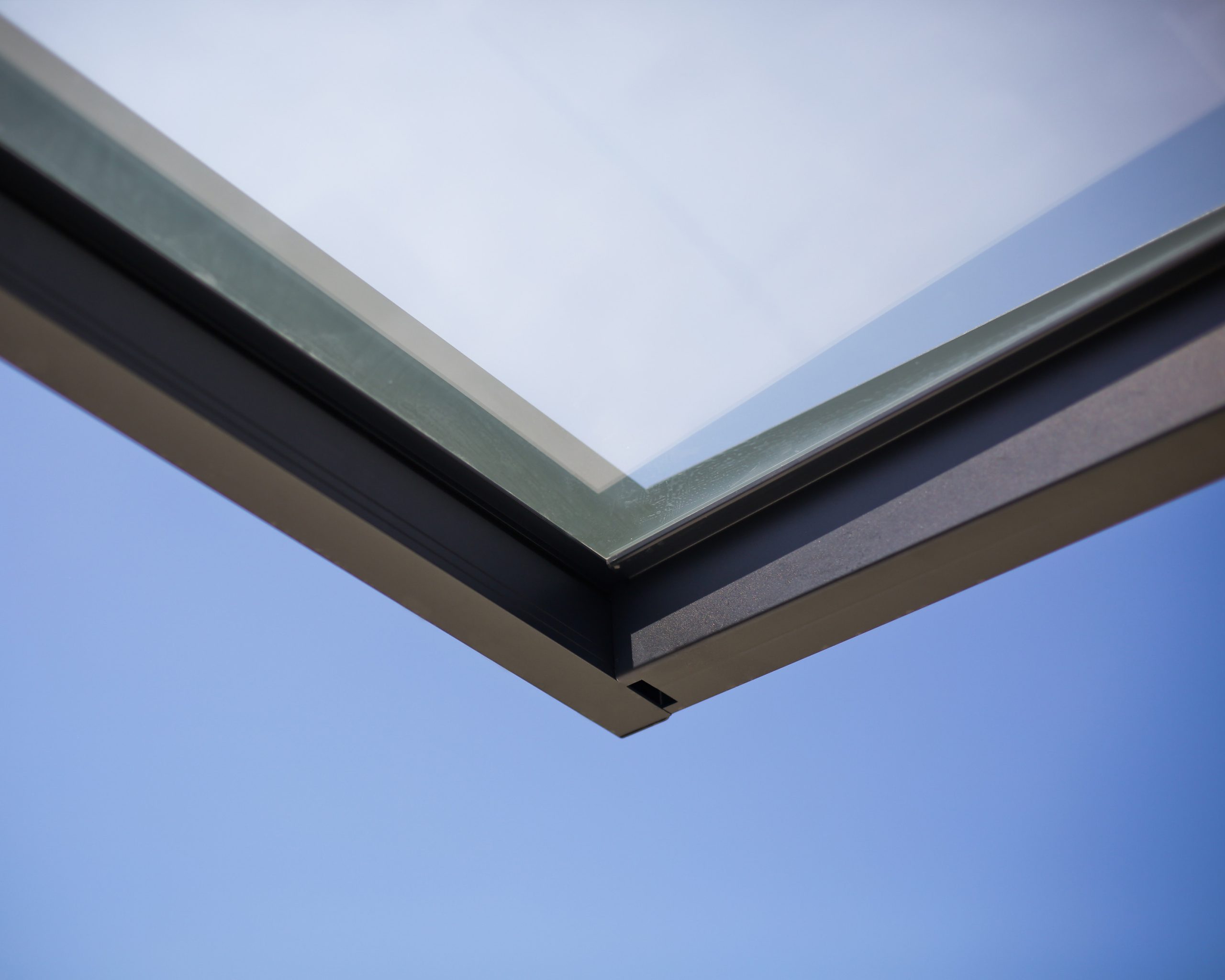 Sophia 2150 door canopy corner detail showcasing gray aluminum frame and clear panel against blue sky, emphasizing modern design and functionality.