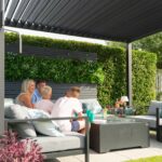 Family enjoying leisure time under a modern NOVA Titan Aluminium Pergola with adjustable louvres, surrounded by greenery, highlighting outdoor living and relaxation.